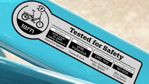 Close-up of an e-bike safety certification label showing compliance with ANSI/CAN/UL 2849, CPSC 1512, and ISO 4210 standards for electrical, frame, and bicycle safety.